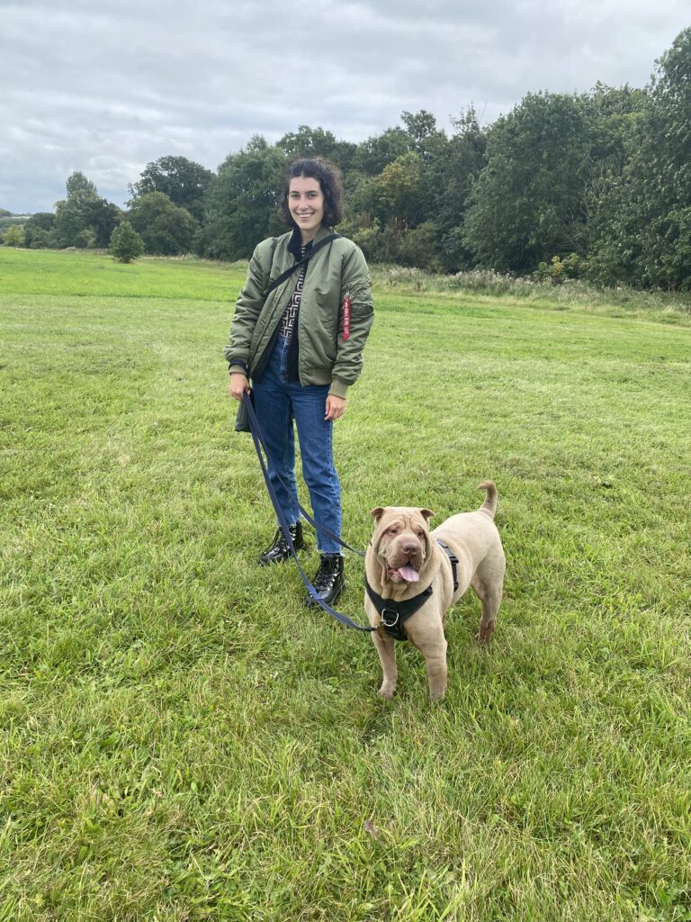 Lauren Sharkey, a dog behaviourist with her dog, Winston, on lead in a grassy area